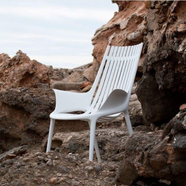 silla blanca de poliporpileno reciclado sobre rocas junto al mar