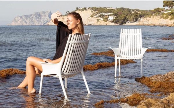 mujer junto al mar sentada en una silla de polipropileno blanco