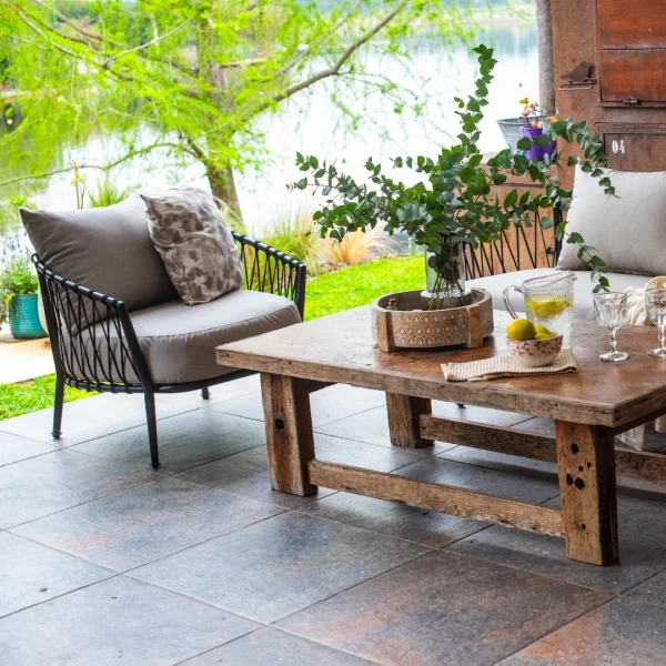 conjunto de sillones de caño y cuerda negro en una galeria con una mesa baja de madera. Ubicados junto a una laguna