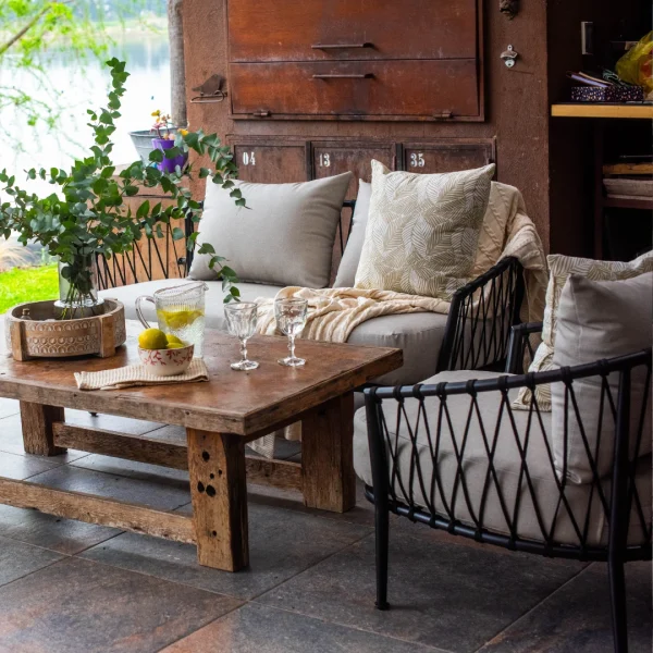 conjunto de sillones de caño y cuerda negro en una galeria con una mesa baja de madera. Ubicados junto a una laguna