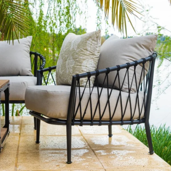 sillón de cuerda y caño negro de perfil en una galería qe da a un lago de fondo