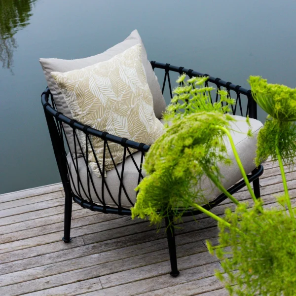 sillón de caño y cuerda negros en un deck junto a una laguna de fondo al atardecer