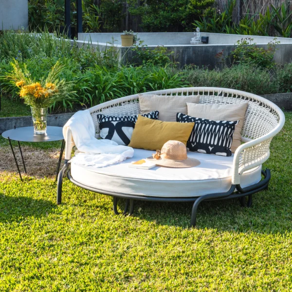 camastro redondo de aluminio y cuerda junto a una mesa de lado en un jardín