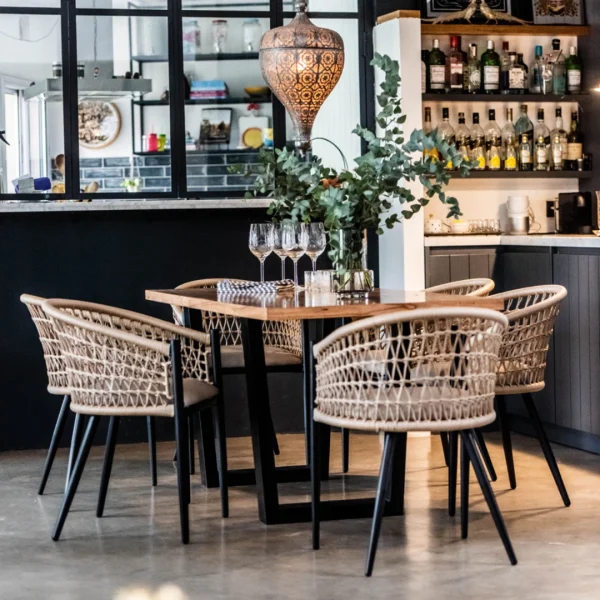 sillas de cuerda trenzada color beige con estructura de hierro negra con una mesa de tapa de madera y patas de hierro negro en un restaurant