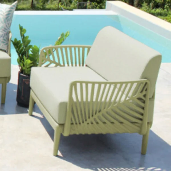 Conjunto de muebles de exterior TROPIC compuesto por un sofá de dos cuerpos, dos sillones individuales y una mesa ratona con tapa de vidrio, junto a una piscina y vista a paisajes verdes.